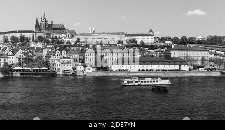 Blick auf das alte Prag an einem Sommertag. Tschechische Republik. Panorama-Schwarzweißfoto. Touristenboot fährt auf der Moldau Stockfoto