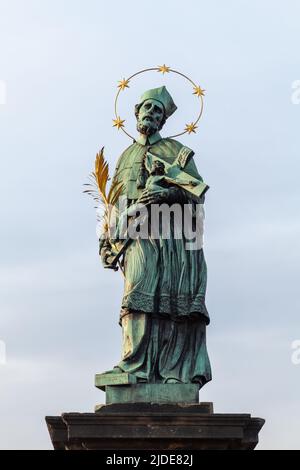 Die Statue des Schutzheiligen Nepomuk an der Karlsbrücke steht tagsüber unter blauem Himmel. Prag. Tschechische Republik Stockfoto