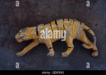 Nahaufnahme eines zerschlagenen und zerkratzten Bleimodells des Tigers in Stalking-Position, das auf rostigen Metallblechen liegt Stockfoto