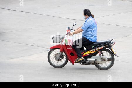 SAMUT PRAKAN, THAILAND, APR 02 2022, Ein Mann mit Gesichtsmaske fährt ein Motorrad Stockfoto