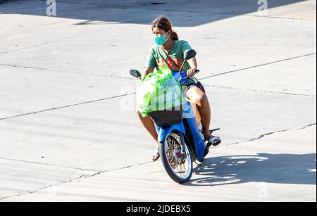 SAMUT PRAKAN, THAILAND, JUNI 10 2022, Eine Frau mit Gesichtsmaske fährt ein Motorrad Stockfoto