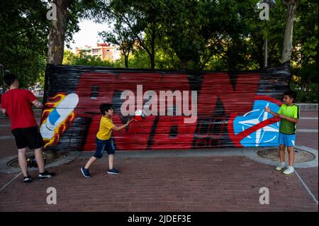 Madrid, Spanien. 19.. Juni 2022. Bei einem Protest im Madrider Stadtteil Vallecas spielen Kinder neben einem Transparent mit der Aufschrift Nein zur NATO. Am 28., 29. Und 30. Juni 2022 wird Spanien Gastgeber eines NATO-Gipfels in Madrid sein. Quelle: Marcos del Mazo/Alamy Live News Stockfoto