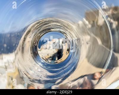 Ein ungewöhnlicher Blick auf die ikonische Oia auf der Insel Santorini, gesehen durch den Boden eines Wasserglases Stockfoto