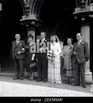 1953, historisch, Hochzeit, eine Braut und ein Bräutigam mit ihren Eltern, die vor der Kirche für ein Foto stehen, England, Großbritannien Stockfoto