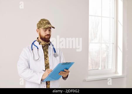 Porträt eines Militärarztes in Tarnuniform und medizinischem Laborkittel mit Klemmbrett Stockfoto