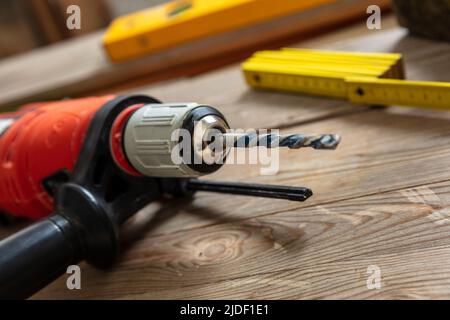 Elektrische Bohrmaschine auf Tischarbeitstisch Zimmermannsfläche Nahaufnahme. Hausreparatur, diy und Fix-Konzept Stockfoto