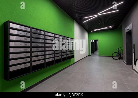 Korridor Halle innen, mit Haustür und Aufzug in vielen Wohngebäude, mit Briefkästen mit grünen Wänden Stockfoto