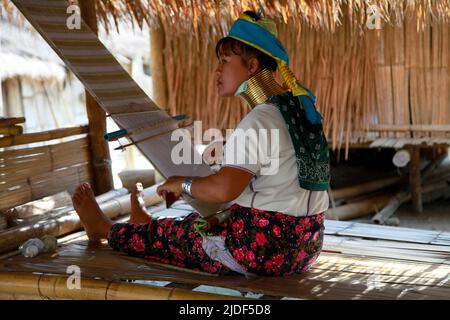 Huai seau Tao, Thailand - 04 2012. August: Junge Frau des Kayan Lahwi Stammes webt einen weißen und goldenen Schal. Stockfoto