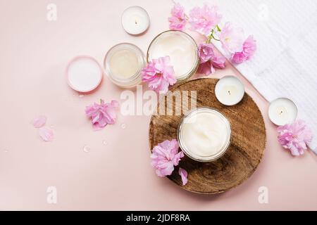 Körperpflegecreme und rosa Kirschblüten. Flach liegend. Stockfoto