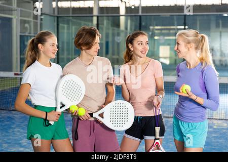 Vier Padel-Spieler stehen vor Gericht und unterhalten sich Stockfoto