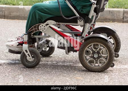 Rollstuhl und kurzer Mann in ihm im Park Stockfoto