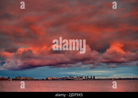 Magischer rosafarbener Himmel über dem im Bau befindlichen Wohnkomplex am Ufer des Flusses Neva auf der Insel Vasilievsky bei Sonnenuntergang, Großinsel Stockfoto