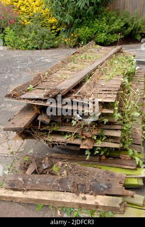 Reste des alten Hausgartenzauns vor dem Haus gestapelt, während sie auf die Abholung zur Entsorgung warten Stockfoto