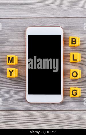 Smartphone mit meinen Blog-Worten auf Holztisch. Nahaufnahme von oben. Stockfoto