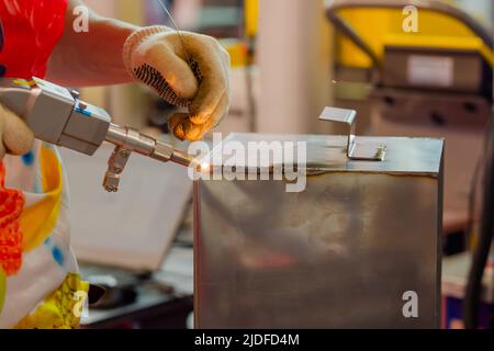 Nahaufnahme: Schweißer Hände mit Handlaserschweißmaschine Stockfoto