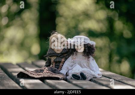 Erstaunlich realistische Vintage Porzellan Puppen, Spielzeug auf grünem Hintergrund Stockfoto