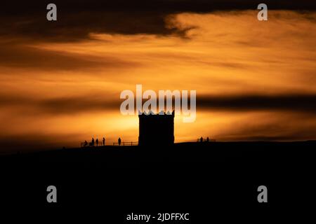 Lancashire, England, Großbritannien, 20.. Juni 2022. Die Sonne untergeht hinter dem Rivington Pike Tower in Lancashire mit von den Wolken reflektierten Farben nach einem warmen und schönen Tag im Nordwesten Englands. Heute ist der letzte Abend des Frühlings, bevor der Sommer morgen, am Tag der Sonnenwende, offiziell beginnt. Quelle: Callum Fraser/Alamy Live News Stockfoto