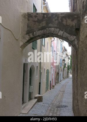 Folgen Sie einem historischen Pfad durch die engen, gewundenen Straßen mit hohen Gebäuden in der malerischen Altstadt von Viviers, Frankreichs kleinster Stadt. Stockfoto