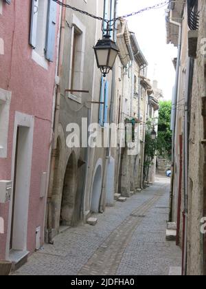 Folgen Sie einem historischen Pfad durch die engen, gewundenen Straßen mit hohen Gebäuden in der malerischen Altstadt von Viviers, Frankreichs kleinster Stadt. Stockfoto