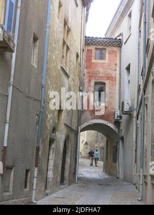 Folgen Sie einem historischen Pfad durch die engen, gewundenen Straßen mit hohen Gebäuden in der malerischen Altstadt von Viviers, Frankreichs kleinster Stadt. Stockfoto