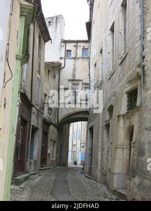 Folgen Sie einem historischen Pfad durch die engen, gewundenen Straßen mit hohen Gebäuden in der malerischen Altstadt von Viviers, Frankreichs kleinster Stadt. Stockfoto