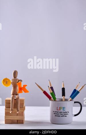 Vertikale Schuss Tasse Bleistifte und Holzfiguren. Dummy hält OK Wort. Platz auf weißem Hintergrund kopieren. Stockfoto