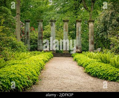 Dorische Säulen und steinerne Löwen, mit Federockenfarnen im Vordergrund. Harlow Carr Gardens, Harrogate. North Yorkshire. VEREINIGTES KÖNIGREICH. Stockfoto