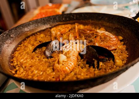 Paella, das traditionelle Gericht in Spanien. Rustikales Gusseisen geschickt gefüllt mit Meeresfrüchte Paella. Reis mit Garnelen, Muscheln Stockfoto