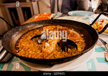 Paella, das traditionelle Gericht in Spanien. Rustikales Gusseisen geschickt gefüllt mit Meeresfrüchte Paella. Reis mit Garnelen, Muscheln Stockfoto