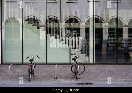 Brussel Old Town, Belgium, 06 19 2022 - das Opernhaus der Monnaie spiegelt sich in der Fassade der flämischen Münzbibliothek wider, an der zwei Fahrräder stehen Stockfoto