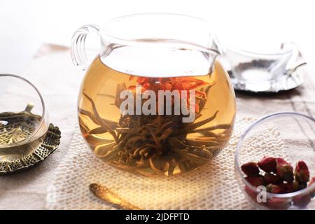 Teekannen- und Glasbecher mit blühender Teeblume im Inneren auf dem Edite-Tisch Stockfoto