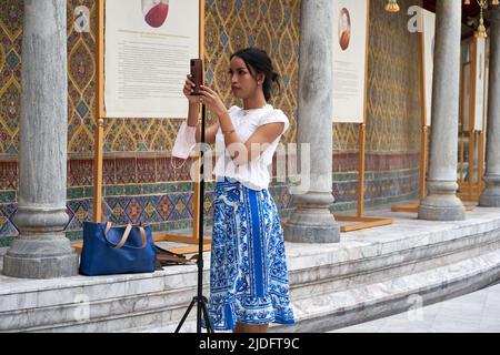 Person, die ein Mobiltelefon am Eingang eines buddhistischen Tempels an einem Stativ befestigt Stockfoto