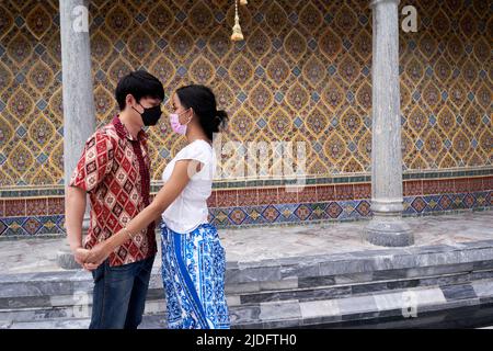 Transgender-Paar, das in einem buddhistischen Tempel in Thailand die Hände hält Stockfoto