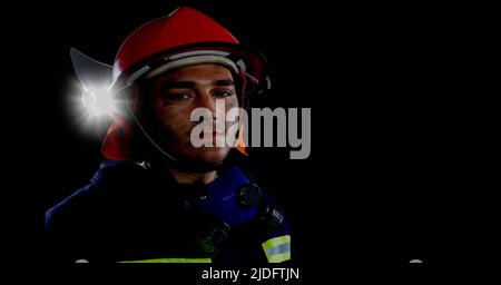 Kaukasischer Feuerwehrmann trägt einen Helm gegen Lichtfleck und kopieren Platz auf schwarzem Hintergrund Stockfoto