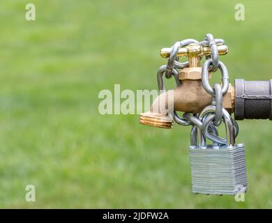 Außenwasserhahn mit Schloss und Kette. Konzept für Wassereinschränkung, Versorgung und Engpässe Stockfoto