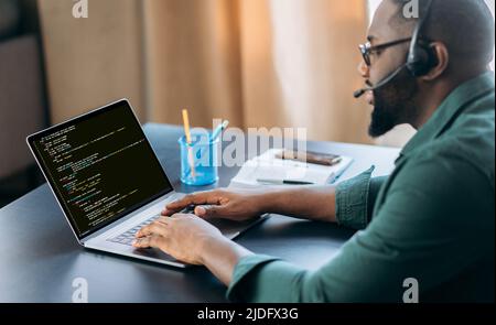 Seitenansicht des erfolgreichen afroamerikanischen IT-Spezialisten, Programmierer, sitzt in einem modernen Büro und arbeitet an der Entwicklung einer Website, Anwendung, Schreiben von Codes und Datencode. Softwarekonzept Stockfoto