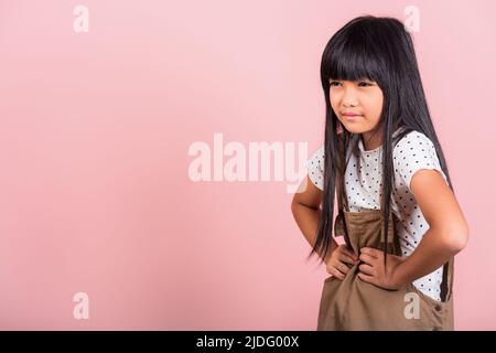 Asiatische kleine Kind 10 Jahre alt leiden an Magenschmerzen im Studio geschossen isoliert auf rosa Hintergrund, glückliches Kind Mädchen Hand halten Magenschmerzen, weil Stockfoto