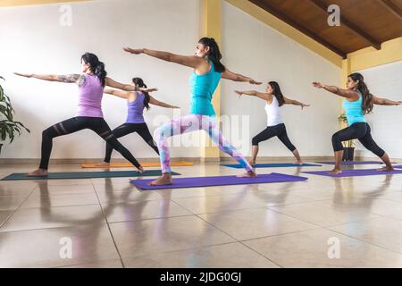 Gruppe von Frauen, die Yoga in Kriegerposition oder Virabhadrasana praktizieren Stockfoto