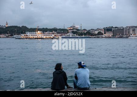 Istanbul, Türkei. 20.. Juni 2022. Ein Paar am Strand von Karakoy mit der Hagia Sophia Moschee im Hintergrund. Gegen Abend in Istanbul werden die Menschen gesehen, wie sie sich im und um den Karakoy Dock gut Vergnügen. (Foto von Onur Dogman/SOPA Images/Sipa USA) Quelle: SIPA USA/Alamy Live News Stockfoto