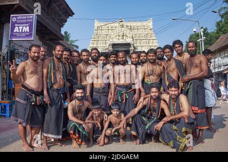 Eine rein männliche Gruppe von Hindu-Pilgern, in schwarzer Dhotis gekleidet, vor dem Padmanabhaswamy-Tempel in Trivandrum (Thiruvananthapuram), Kerala, Indien Stockfoto