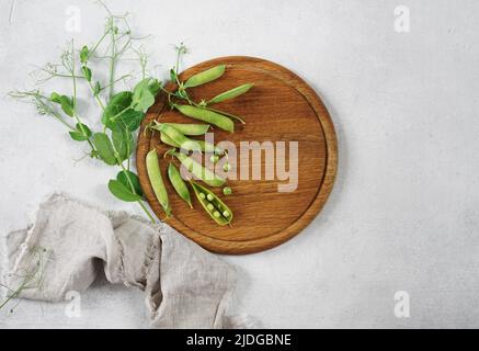 Junge grüne Erbsen auf einem runden Holzbrett auf einem weißen Hintergrund Platz für Text. Flach liegend, Draufsicht Stockfoto
