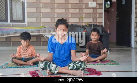 Asiatische Kinder tun Yoga zu Hause posieren. Gruppe von Kindern, die Gymnastik machen. Stockfoto