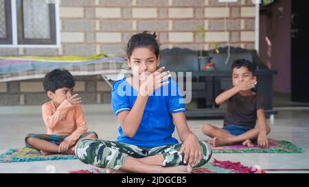 Asiatische Kinder tun Yoga zu Hause posieren. Gruppe von Kindern, die Gymnastik machen. Stockfoto