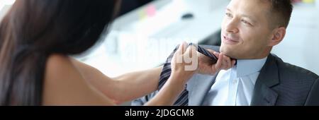 Weibliche Vorgesetzte zieht Krawatte von jungen Angestellten Stockfoto