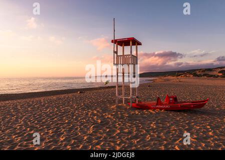 Salvataggio Rettungsschwimmer Wachturm und Rettungsboot am Sandstrand von Piscinas im goldenen Licht bei Sonnenuntergang, Costa Verde, Sardinien, Italien Stockfoto