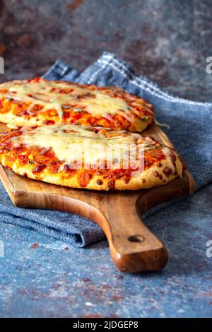Gemüsepizza mit geschmolzenem Käse, gekocht auf einem Holzbrett. Mit einem Geschirrtuch auf einem grunge Hintergrund. Stockfoto