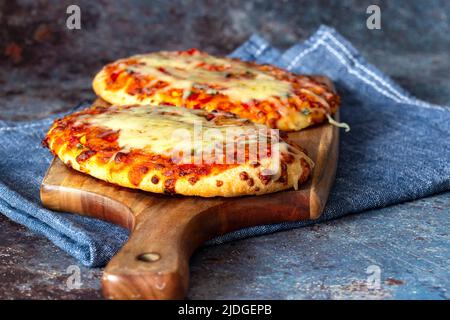 Gemüsepizza mit geschmolzenem Käse, gekocht auf einem Holzbrett. Mit einem Geschirrtuch auf einem grunge Hintergrund. Stockfoto