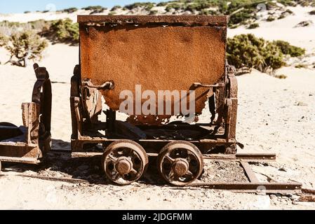 Rostig gebrochene Wagen und Schrott einer Eisenbahn von den Blei- und Zinkminen zu den Sanddünen in der Nähe des Strandes von Piscinas, Costa Verde, Sardinien, Italien Stockfoto