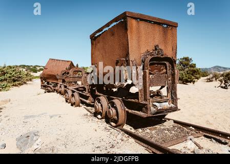 Rostig gebrochene Wagen und Schrott einer Eisenbahn von den Blei- und Zinkminen zu den Sanddünen in der Nähe des Strandes von Piscinas, Costa Verde, Sardinien, Italien Stockfoto