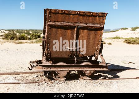 Rostig gebrochene Wagen und Schrott einer Eisenbahn von den Blei- und Zinkminen zu den Sanddünen in der Nähe des Strandes von Piscinas, Costa Verde, Sardinien, Italien Stockfoto